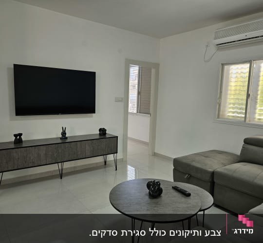 סלון עם טלוויזיה תלויה, מזגן וספה אפורה